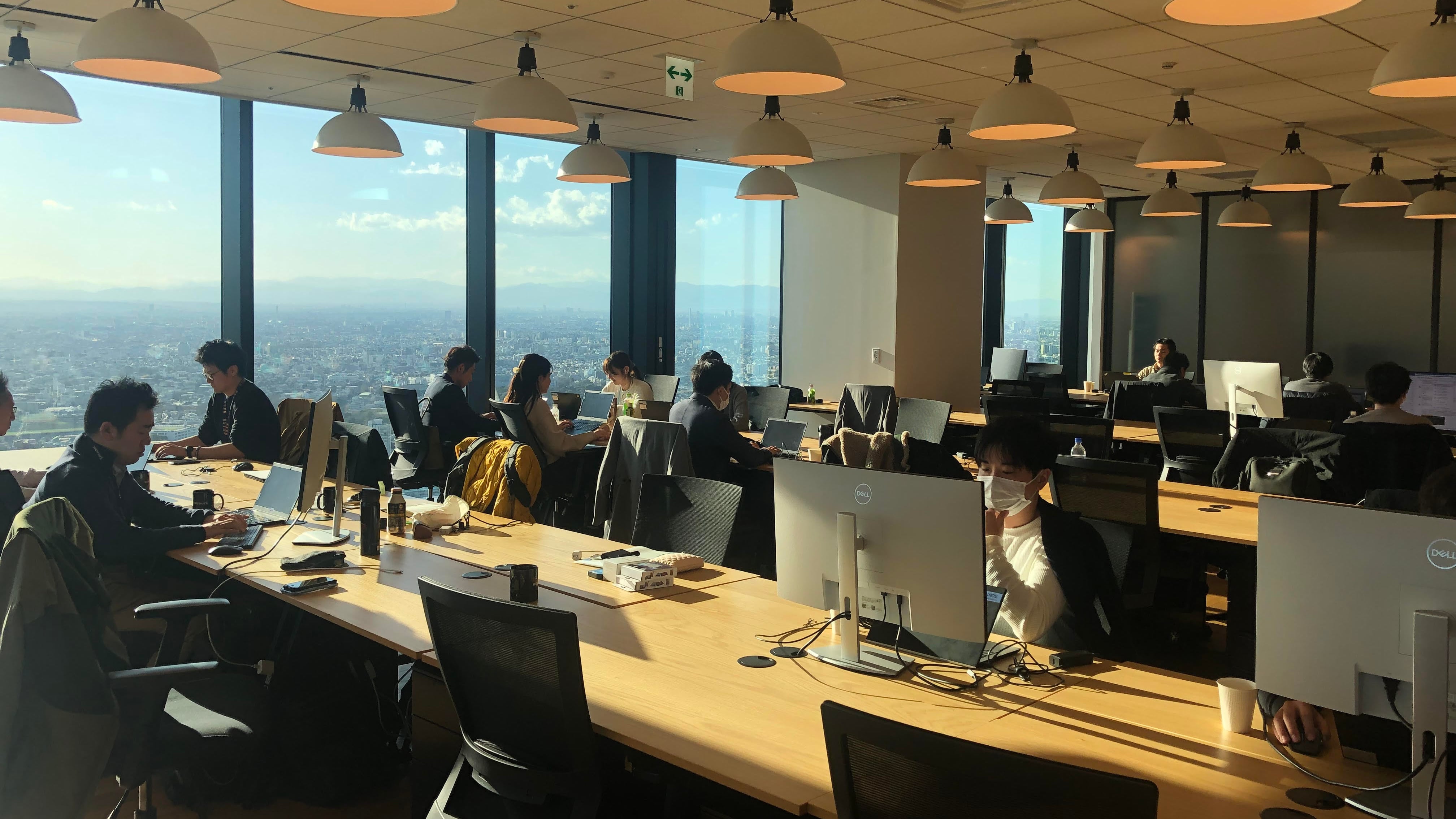 people sitting in an open office space at a Subaru office in Tokyo Japan next to a window.